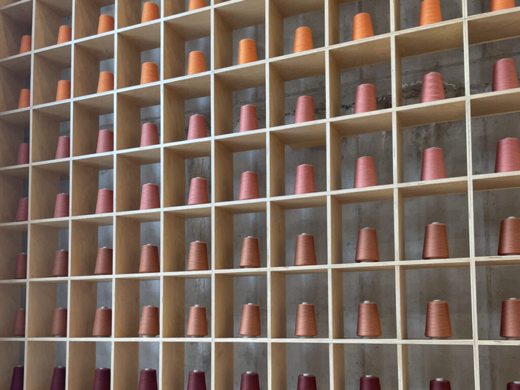 Front-facing view of a modern yarn store with neatly organized shelves filled with colorful yarn skeins. Clean white shelving and warm wood accents make this a featured location in a Where to Buy Yarn in Seoul Shops Guide for knitting and crochet enthusiasts.